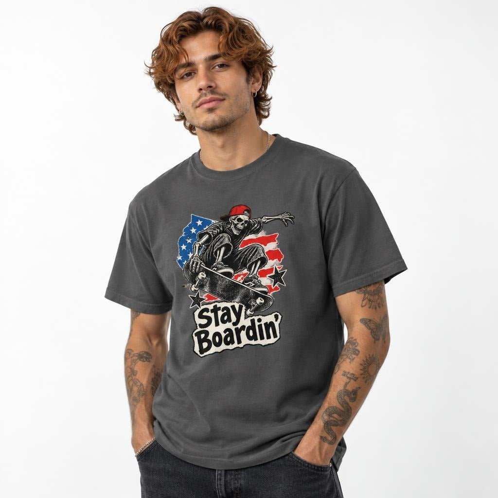 Front view of a Pepper T-shirt with a distressed skateboard and skeleton graphic, American flag details, and “Stay Boardin’” text.