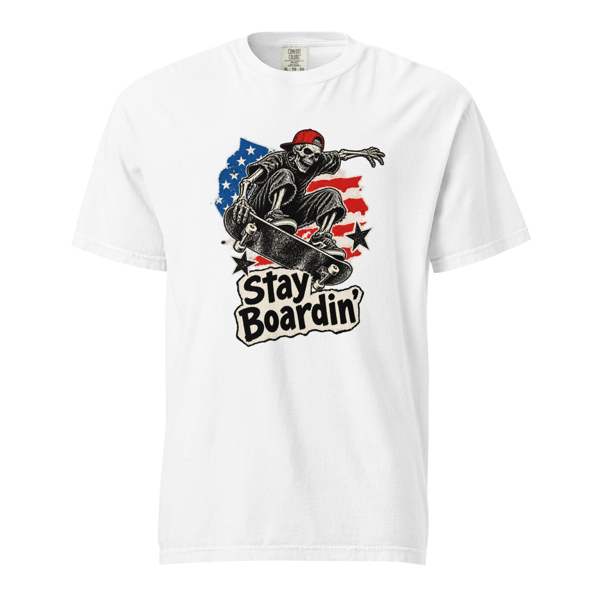 Front of a white T-shirt featuring a skeleton in a red cap riding a skateboard with American flag details and “Stay Boardin’” text.