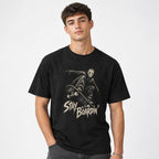 Model wearing a black T-shirt with a masked skater riding a skateboard above distressed Stay Boardin’ lettering.