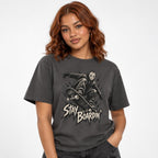Front model view of a graphite T-shirt with a masked skater crouching on a skateboard above distressed “STAY BOARDIN’” lettering.