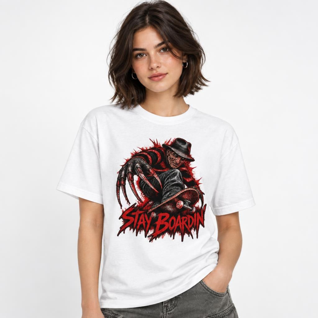 Front view of a model wearing a white T-shirt with a dark horror figure, skateboard, and distressed red “STAY BOARDIN’” graphic.