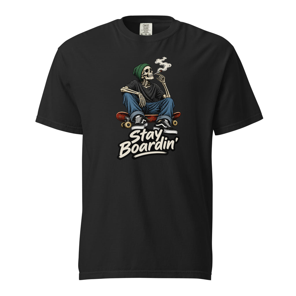 Front view of a black T-shirt with a seated smoking skeleton wearing a green beanie on a skateboard above “Stay Boardin’” lettering.
