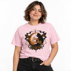 Model wearing a Blossom Stay Spooky T-shirt featuring a black cat, golden crescent moon, pumpkins, moths and stars in a gothic vintage design.