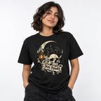 Model wearing a black T-shirt featuring a black cat with amber eyes resting on a skull beside a glowing lantern and Stay Spooky banner