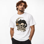 White T-shirt featuring a black cat with amber eyes resting on a skull beside a glowing lantern, crescent moon, and “Stay Spooky” banner.