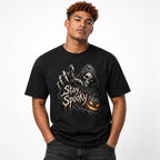 Model wearing a black T-shirt with distressed “Stay Spooky” lettering, a hooded grim reaper skeleton, and a glowing pumpkin.