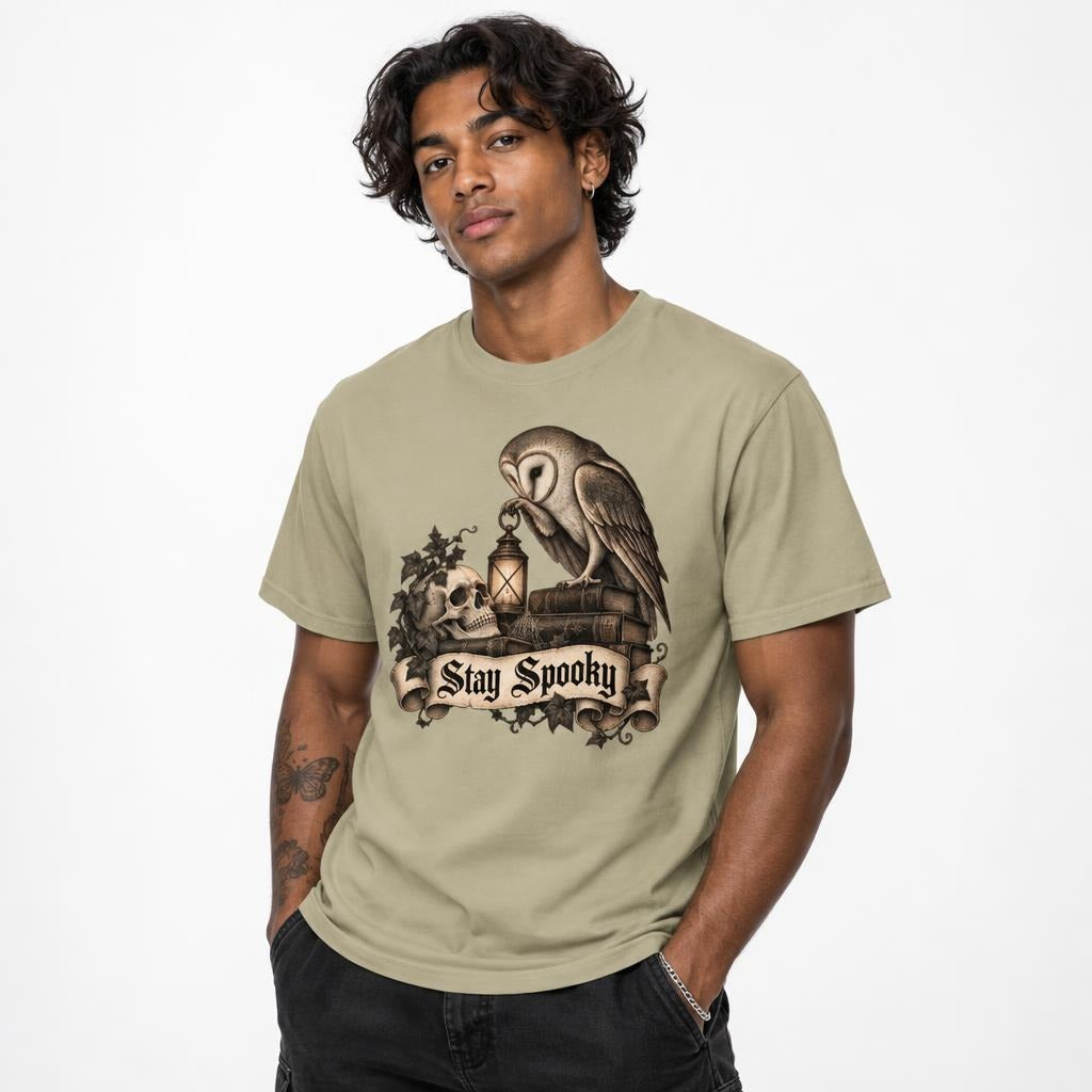 Front view of a khaki T-shirt on a model, featuring “Stay Spooky” with an owl, skull, lantern, books and ivy in a vintage gothic illustration.