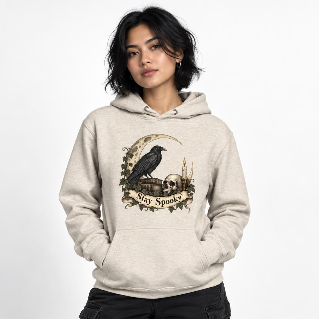 Front view of an Oatmeal Heather hoodie featuring a raven, skull, crescent moon, candle and “Stay Spooky” scroll artwork.