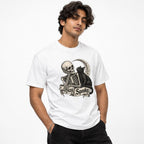 Front view of a person wearing a white T-shirt with a skeleton, black cat, crescent moon, and “Stay Spooky” banner.