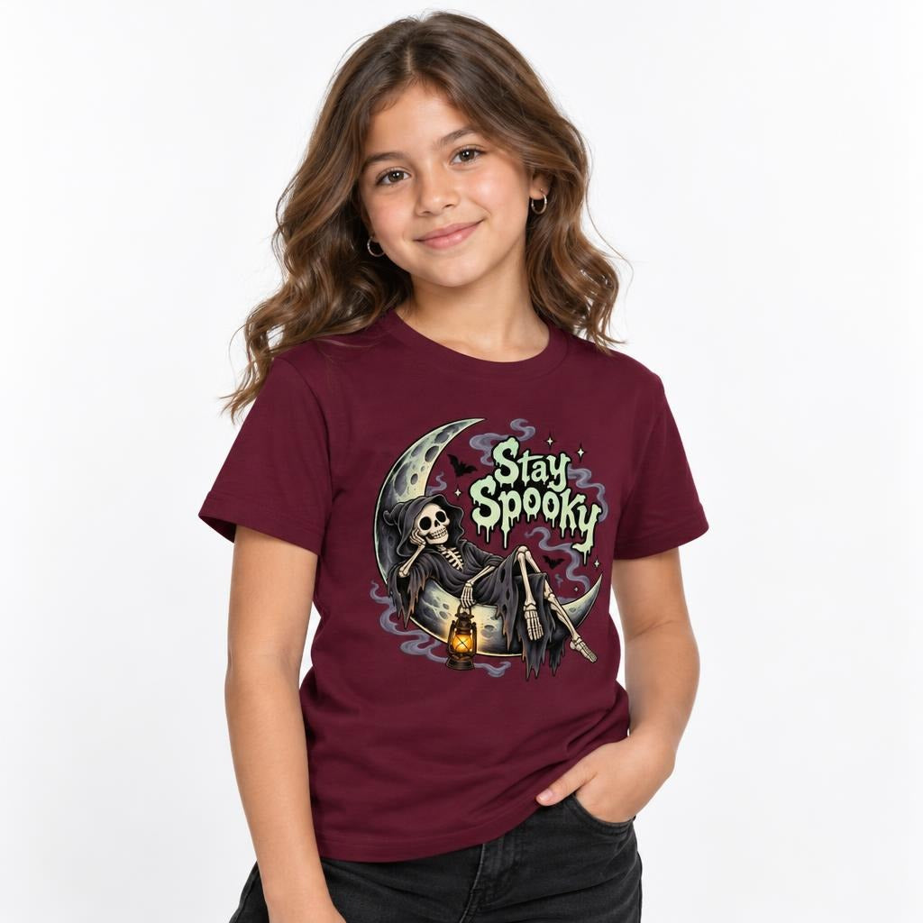 Front view of a child wearing a Maroon T-shirt with a “Stay Spooky” graphic of a skeleton, crescent moon and lantern.