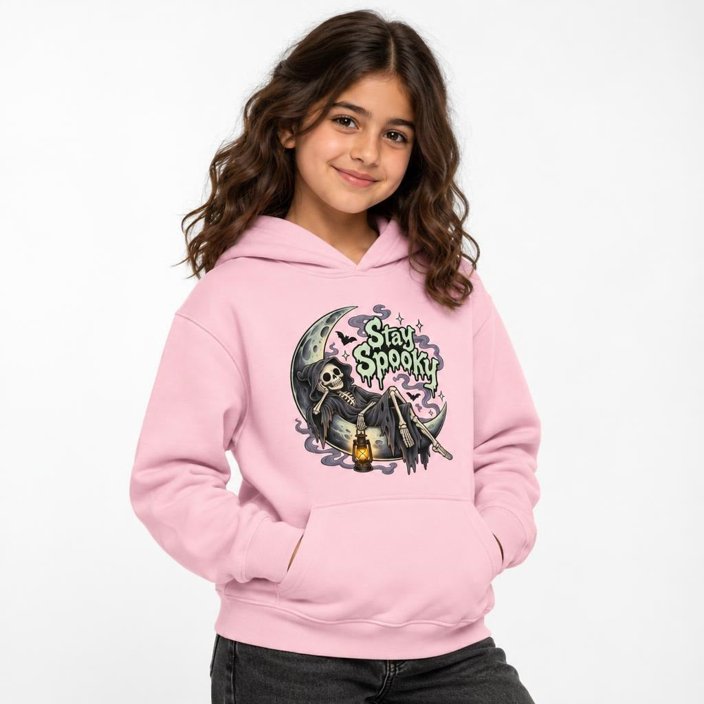 Model wearing a Light Pink hoodie with a front “Stay Spooky” graphic of a skeleton reclining on a crescent moon with a lantern.