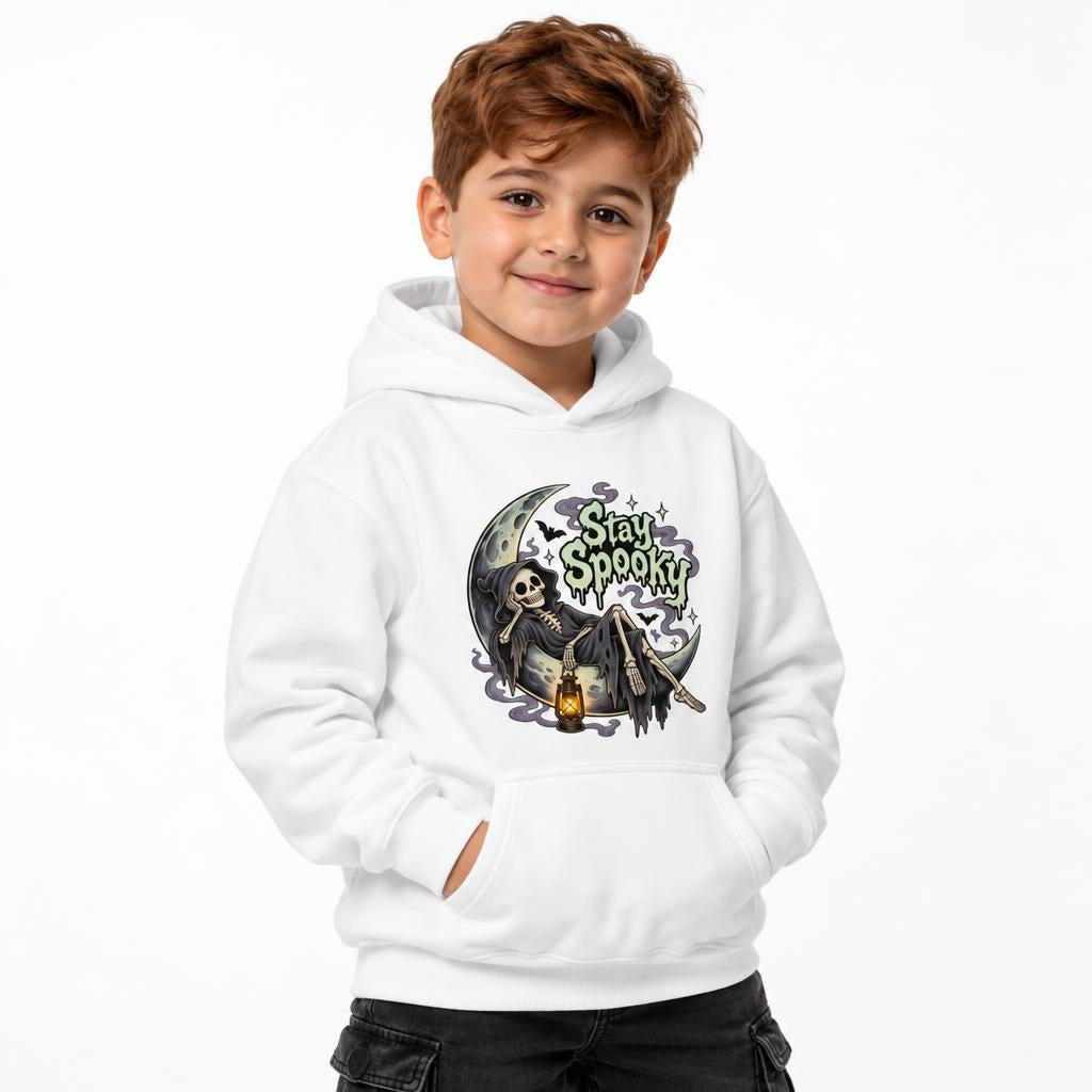 Front view of a child wearing a white hoodie with a Stay Spooky graphic of a skeleton on a crescent moon holding a lantern.