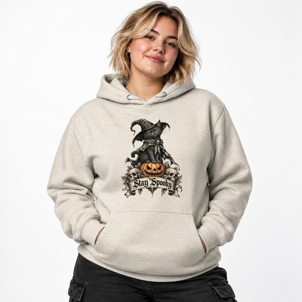 Model wearing an Oatmeal Heather hoodie with a black cat in a witch hat sitting on an orange pumpkin and Stay Spooky lettering.