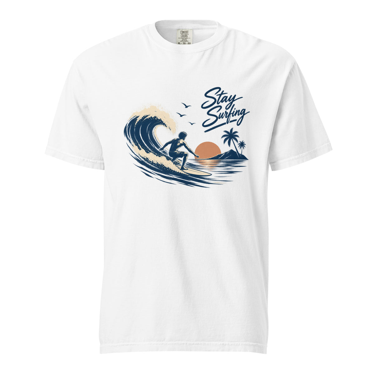 White T-shirt featuring a surfer riding a curling wave with palm trees, birds, sunset tones, and “Stay Surfing” script.