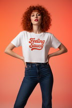Model wearing the Feeling Saucy Retro Script Crop Top in an orange studio scene with jeans