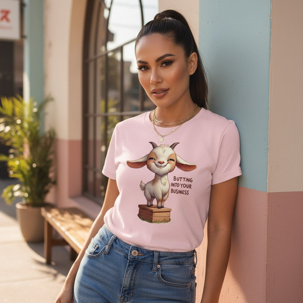 Woman wearing a pink t-shirt with a cartoon goat graphic and text, standing against a building.