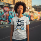 Person wearing a t-shirt with a penguin graphic and text in an urban setting with graffiti.