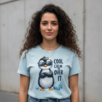 Woman wearing a light blue t-shirt with a penguin graphic and text, standing against a plain background.