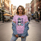Woman wearing a pink t-shirt with a penguin graphic and text on a city street.