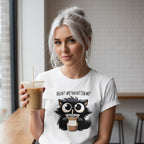 Woman wearing a white t-shirt with a black cat graphic and text, holding a coffee drink.