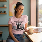 Woman wearing a pink t-shirt with a graphic design, sitting at a desk holding a mug.