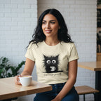 Woman wearing a t-shirt with a cat graphic and text, sitting at a table with a cup of coffee.