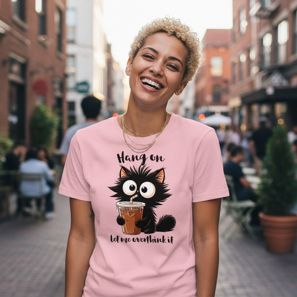 Person wearing a pink t-shirt with a cat graphic and text in an urban setting