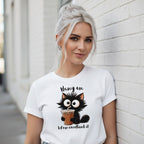 Woman wearing a white t-shirt with a cat graphic and text, leaning against a light-colored wall.