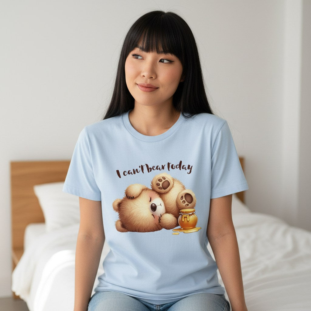 Person wearing a light blue t-shirt with a bear graphic and text, sitting on a bed.