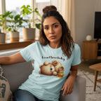 Woman wearing a light blue t-shirt with a bear graphic and text, sitting on a couch in a living room.