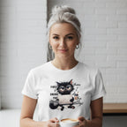 Woman wearing a white t-shirt with a cat graphic and text, holding a coffee cup.