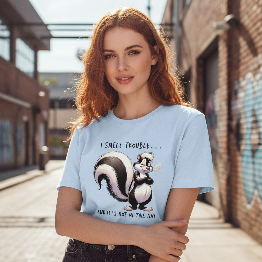 Woman wearing a light blue t-shirt with a cartoon skunk design and text, standing on a street.