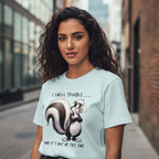 Woman wearing a light blue t-shirt with a skunk graphic and text in an urban setting