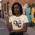 Person wearing a t-shirt with a skunk graphic and text, standing in an urban setting with graffiti.