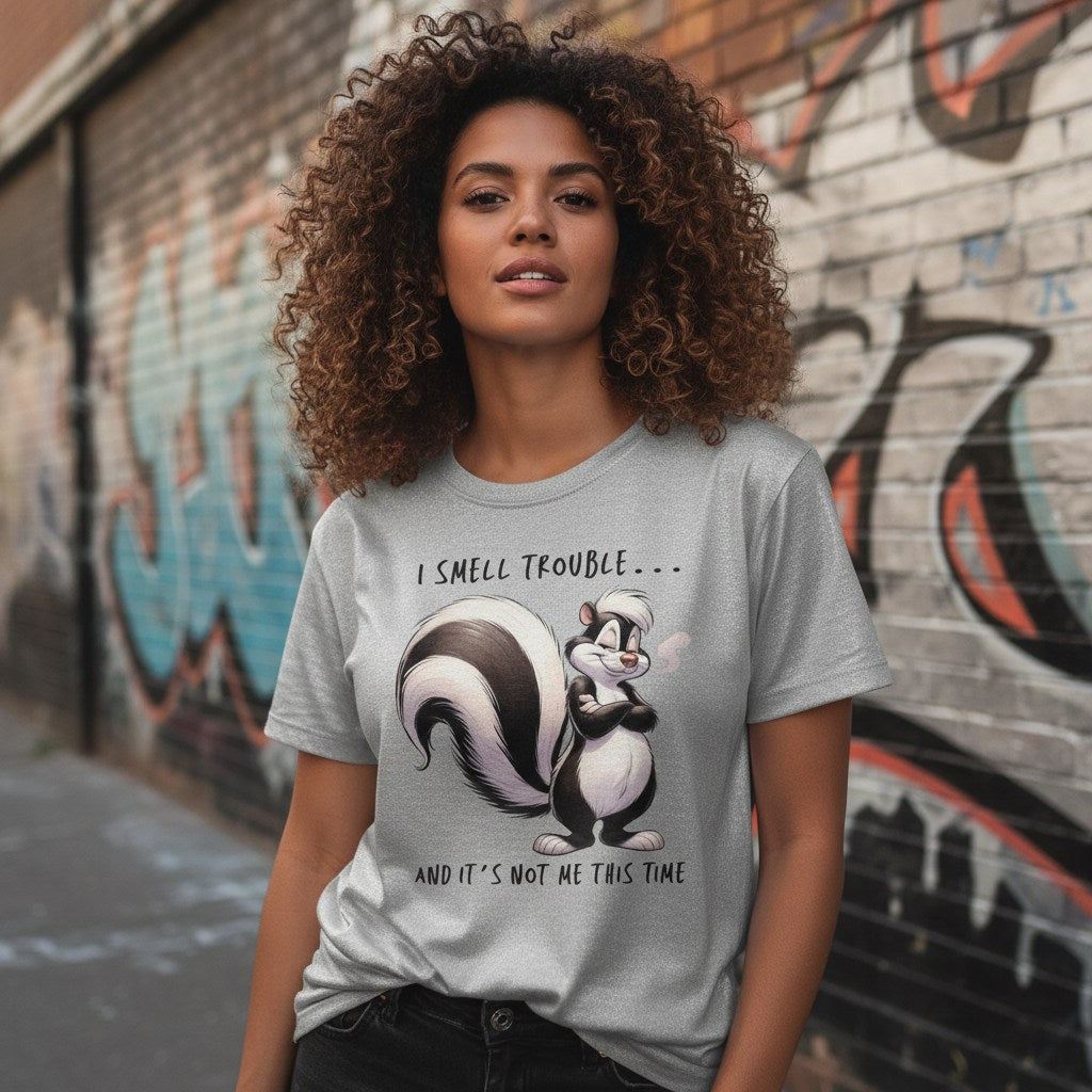 Woman wearing a t-shirt with a skunk graphic and text in front of a graffiti-covered wall.