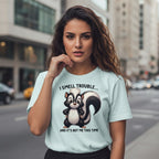 Woman wearing a light blue t-shirt with a skunk graphic and text on a city street.