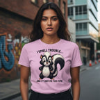 Woman wearing a pink t-shirt with a skunk graphic and text in an urban setting