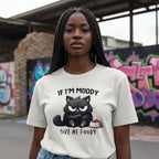 Person wearing a white t-shirt with a cat graphic and text in an urban setting
