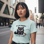 Woman wearing a light blue t-shirt with a black cat graphic and text on a city street.
