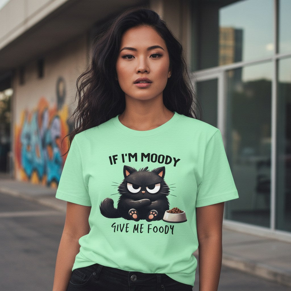 Woman wearing a green t-shirt with a black cat graphic and text in an urban setting.
