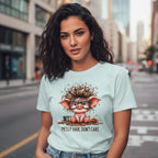 Woman wearing a light blue t-shirt with a cartoon pig design on a city street.