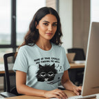 Woman wearing a t-shirt with a cat graphic and text, sitting at a desk.