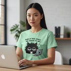 Woman wearing a light green t-shirt with a black cat graphic and text, using a laptop.