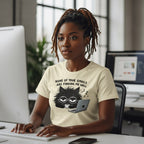 Person wearing a t-shirt with a cat graphic and text, sitting at a desk in an office setting.