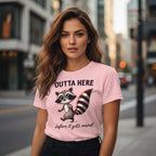 Woman wearing a pink t-shirt with a raccoon graphic and text on a city street.