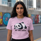 Woman wearing a pink t-shirt with a panda graphic and text, standing in an urban setting.