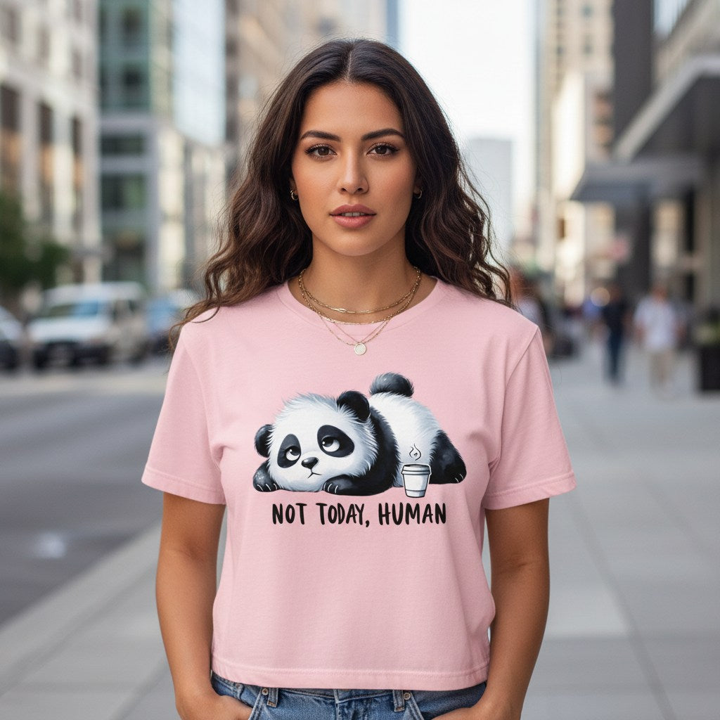 Woman wearing a pink t-shirt with a panda graphic and text on a city street.