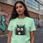 Woman wearing a light green t-shirt with a cartoon character and text, standing in an urban setting with graffiti.