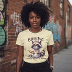 Woman wearing a t-shirt with a raccoon graphic and text, standing in front of a graffiti-covered wall.