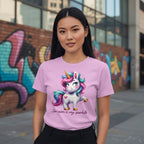 Person wearing a pink t-shirt with a unicorn graphic and text, standing in front of colorful graffiti.